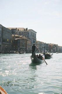 Sunlit gondolas gently floating along Venice’s serene canals framed by old stone bridges