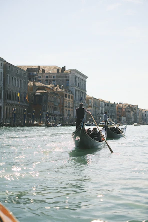 Elegant gondola gliding through Venice’s shimmering canals under historic bridges.