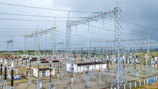 A team of technicians inspecting high-voltage transmission towers surrounded by green landscape.