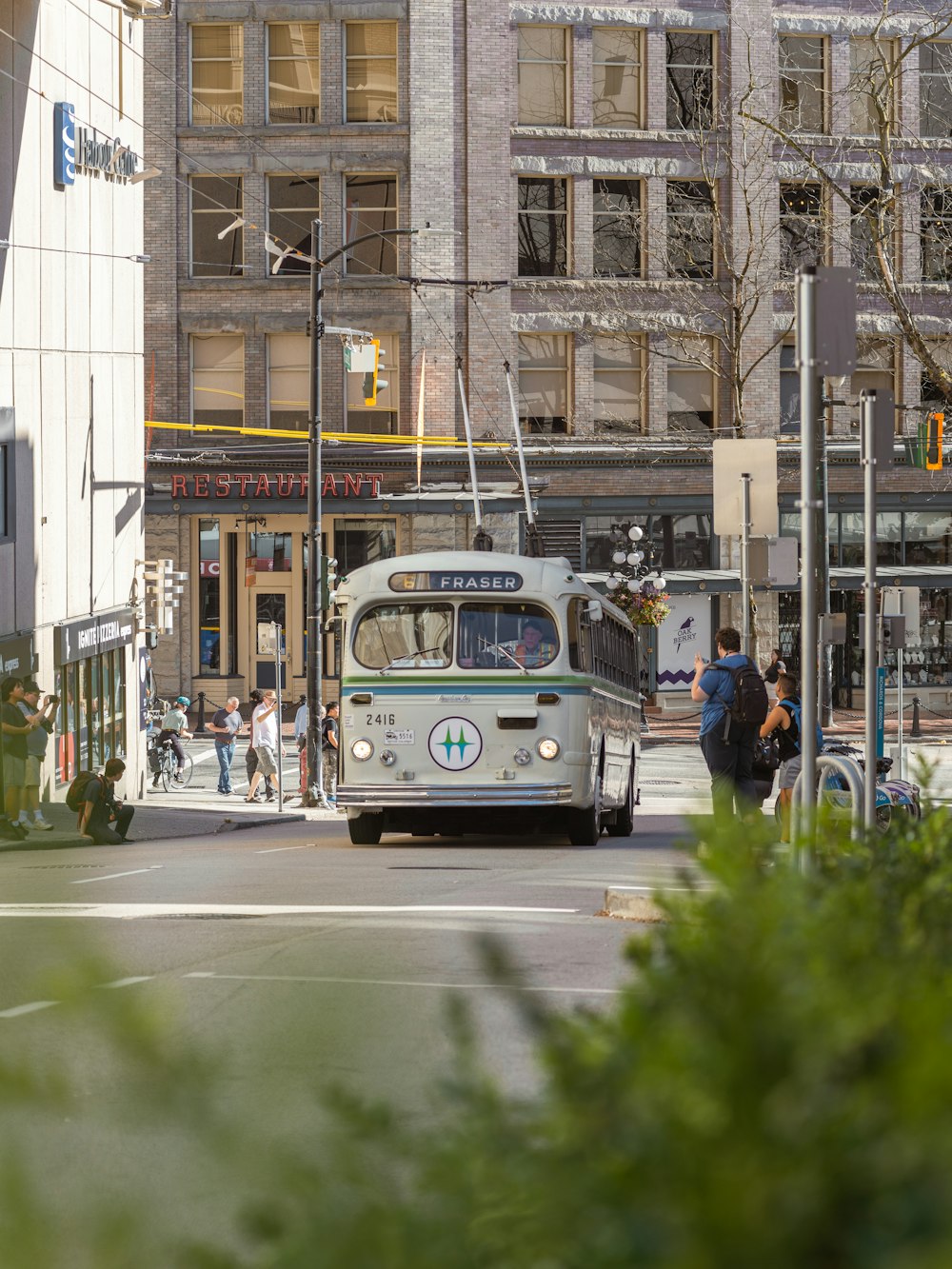 a white bus driving down a street next to tall buildings