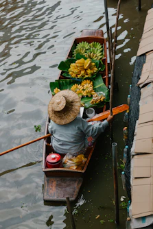 a person in a boat with bananas and other items