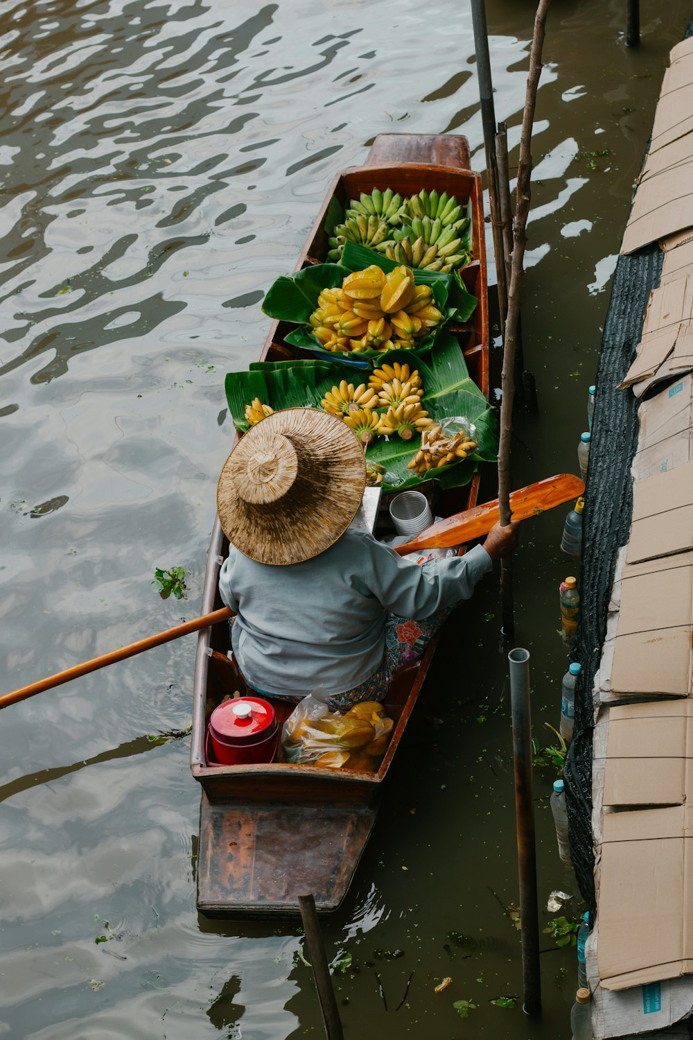 Una persona en un bote con plátanos y otros artículos