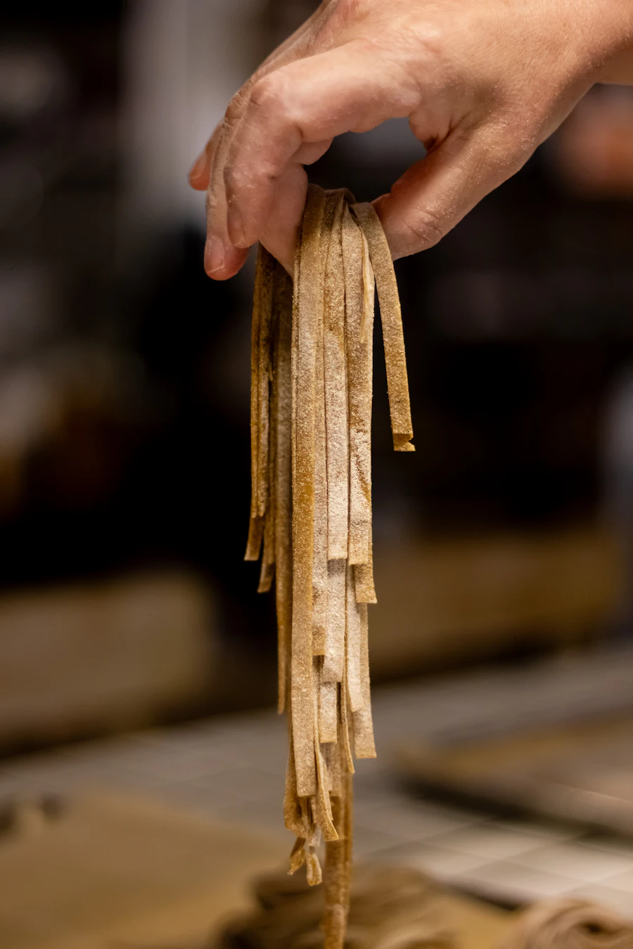 Hands holding fresh handmade pasta strands at Makaron Leicester