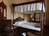 A king-sized bed with a vintage wooden frame and plush decorative pillows.