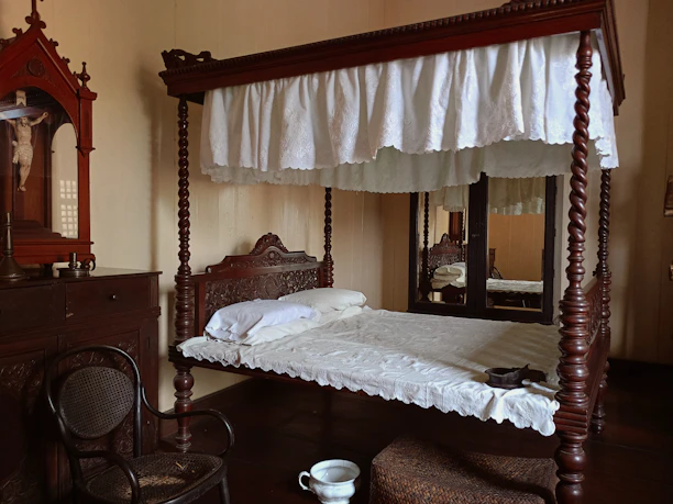 Classic wooden four-poster bed styled with vintage linens and warm decor.