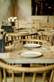 a restaurant with wooden tables and chairs with white plates on them