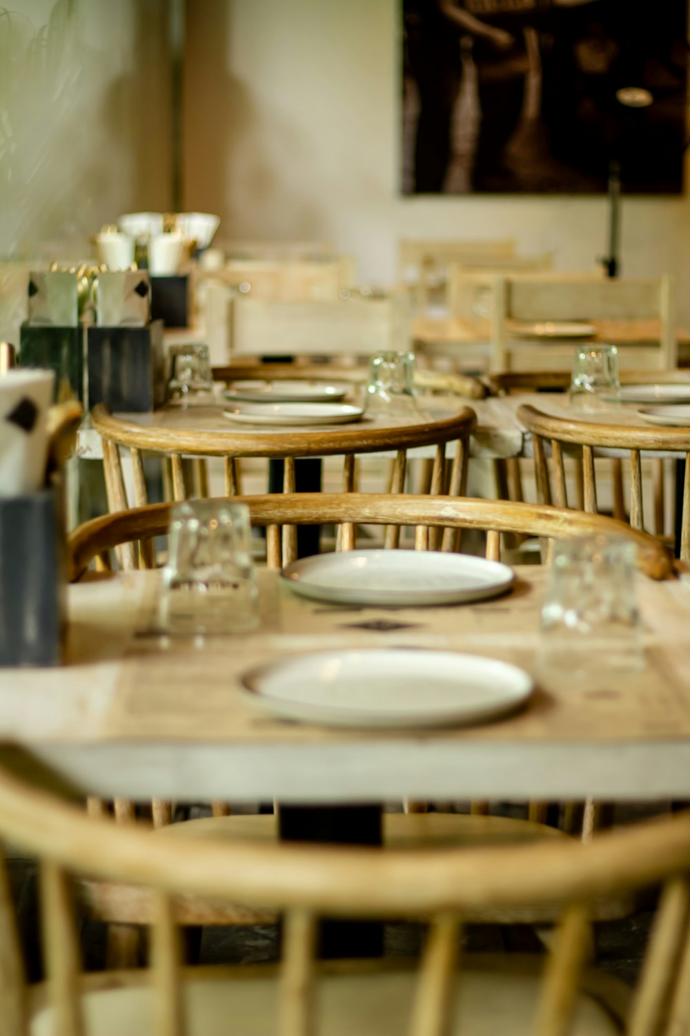 um restaurante com mesas e cadeiras de madeira com pratos brancos