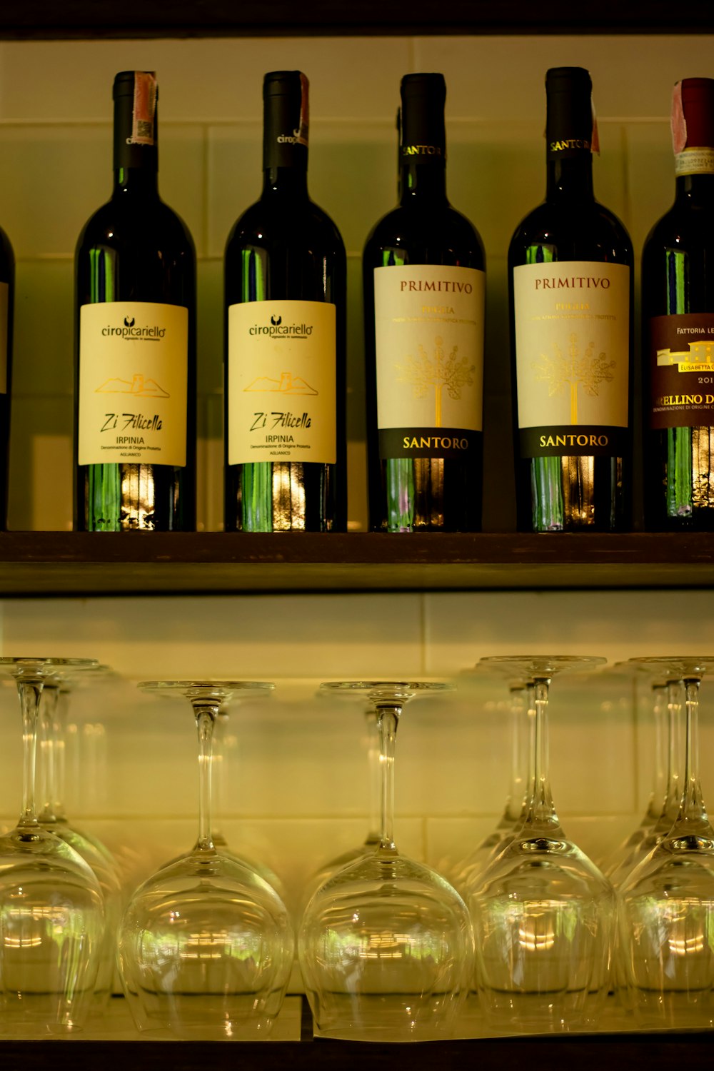 a row of wine glasses sitting next to bottles of wine