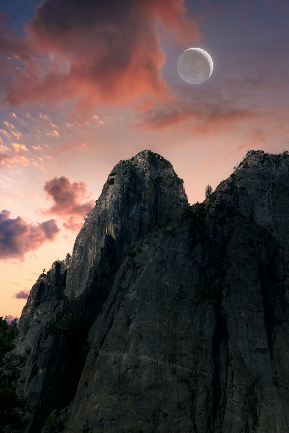 the moon is setting over a rocky mountain