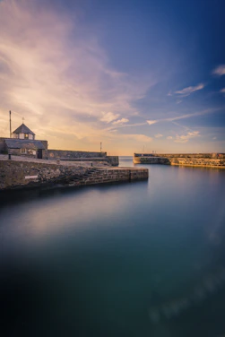 A serene view of Cap Valéor’s historic harbor bathed in warm sunset light.