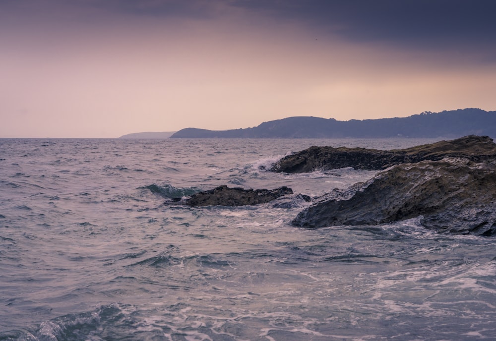 a large body of water sitting next to a rocky shore