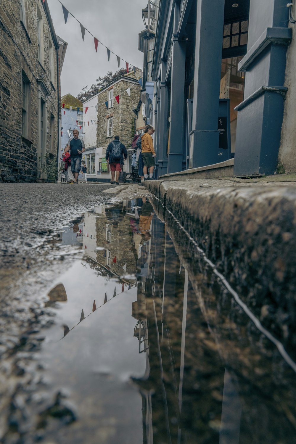 a group of people walking down a street next to a puddle