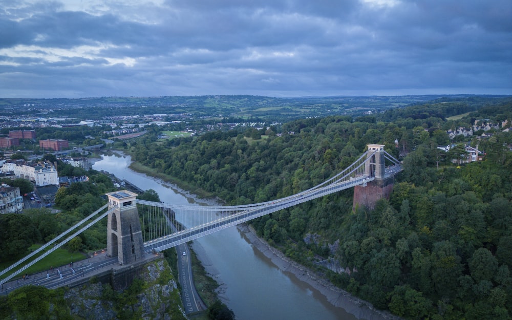 a suspension bridge over a river in a city