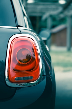 Original stoplamp shining brightly on a red sedan in daylight