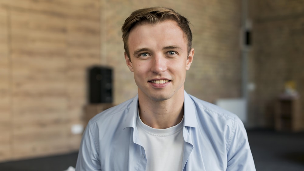 a man in a blue shirt smiles at the camera