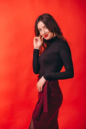 A warm editorial photo of a confident woman wearing terracotta-accented apparel against a cream ivory backdrop.