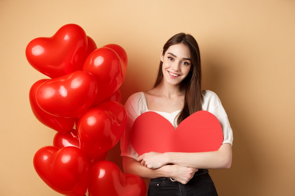 a woman holding a red heart shaped balloon