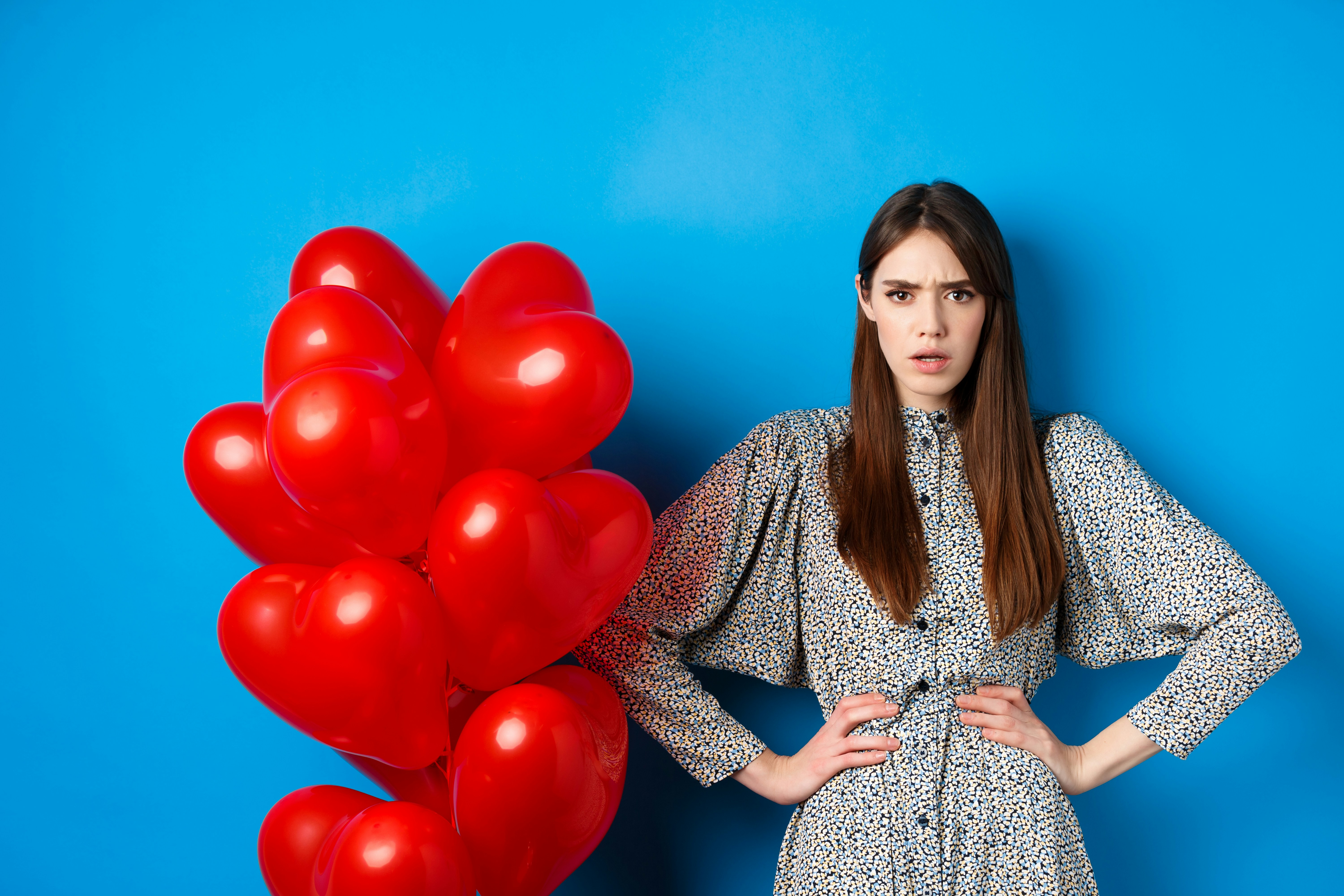 a woman standing next to a bunch of red balloons