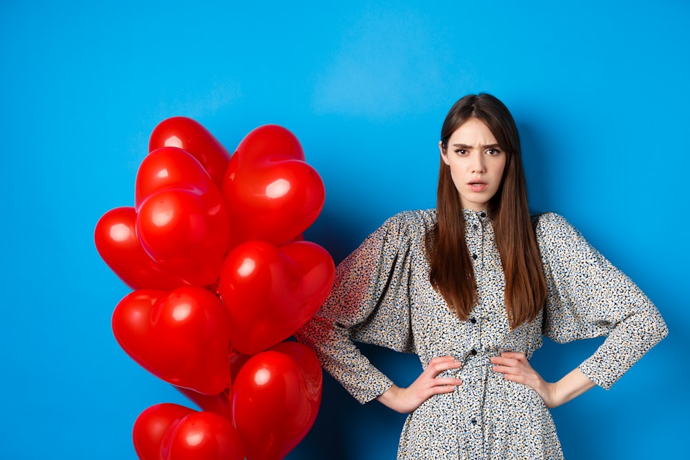 a woman standing next to a bunch of red balloons