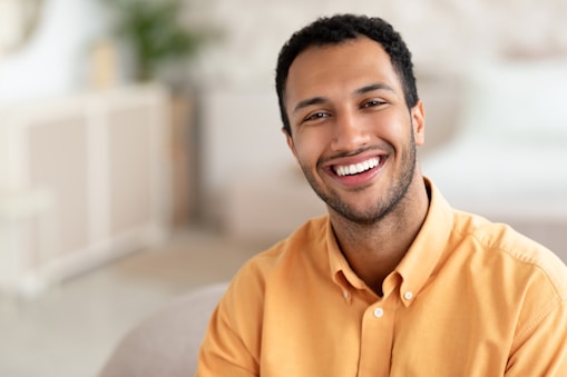 a smiling man sitting on a couch in a living room