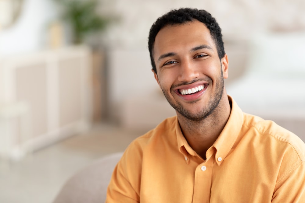 a smiling man sitting on a couch in a living room