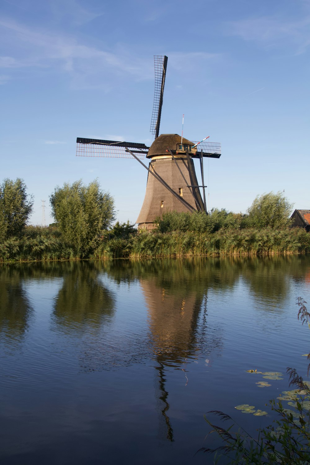 a windmill sitting on top of a lake next to a forest