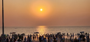 Crowd gathered by the beach during a vibrant sunset in Rio Vermelho