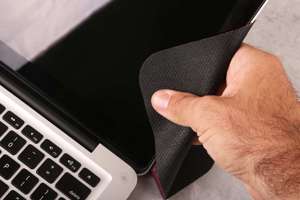 una mano che tiene un panno sopra un computer portatile