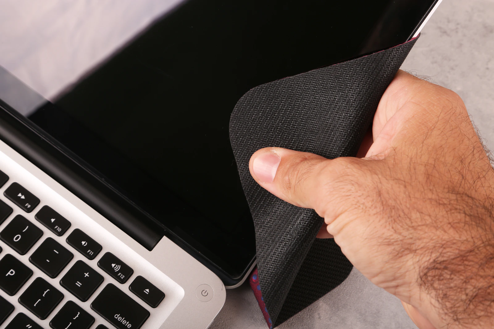 Hand gently cleaning a laptop with a soft cloth