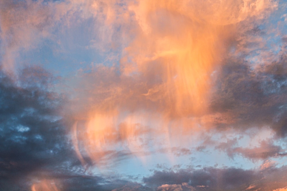 a cloudy sky with a plane in the foreground