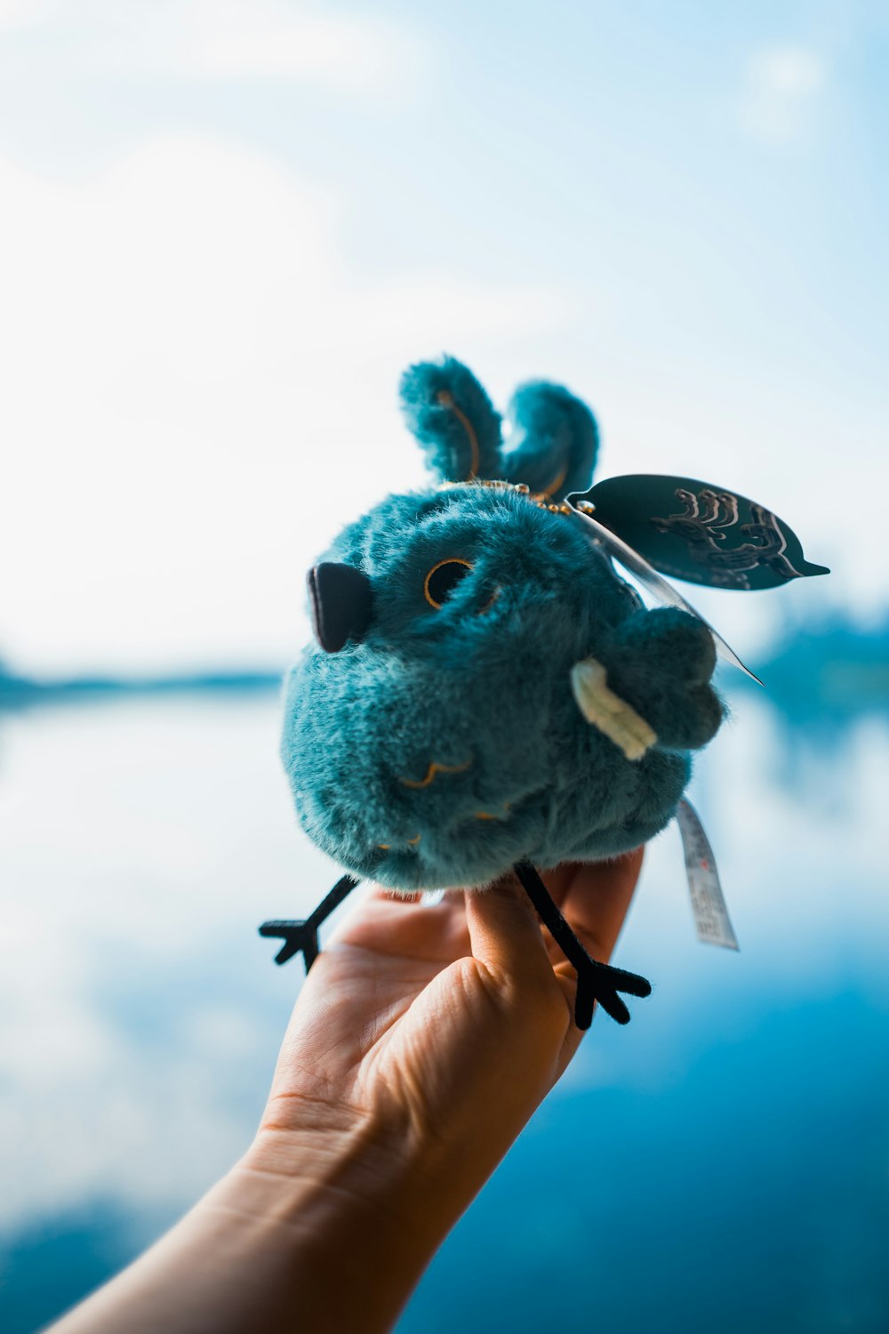 a hand holding a small stuffed animal with a leaf on it