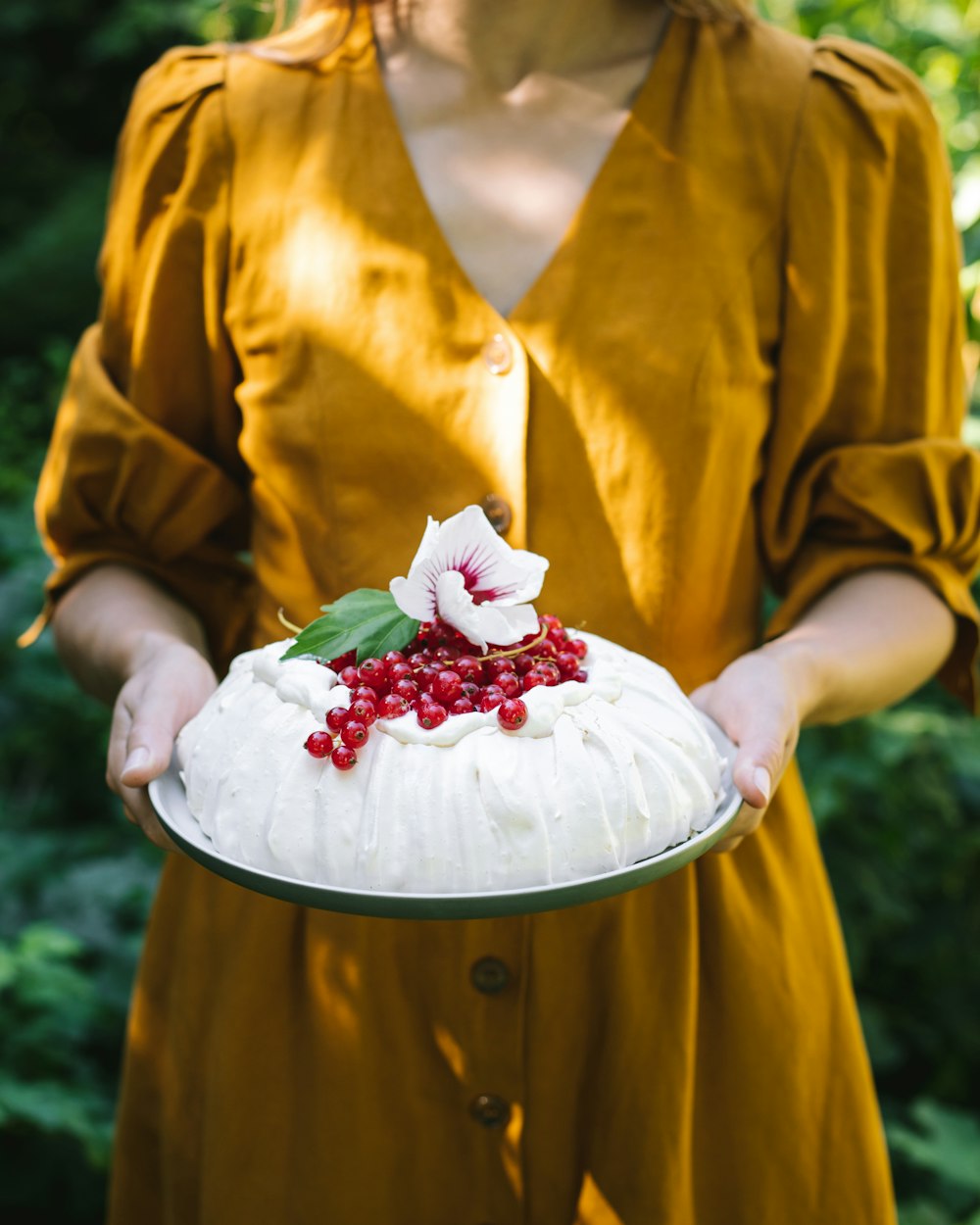 a woman in a yellow dress holding a cake