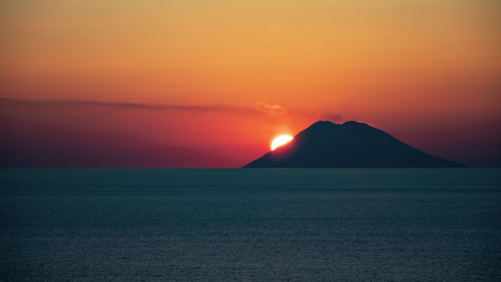 the sun is setting over a small island in the middle of the ocean