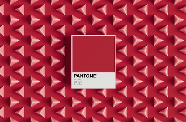 A pattern of three-dimensional red and pink pyramids on a red background with a central focus on a Pantone color swatch labeled 'True Red', including the color code 19-1664 and hex code #BF1932.