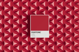 A pattern of three-dimensional red and pink pyramids on a red background with a central focus on a Pantone color swatch labeled 'True Red', including the color code 19-1664 and hex code #BF1932.