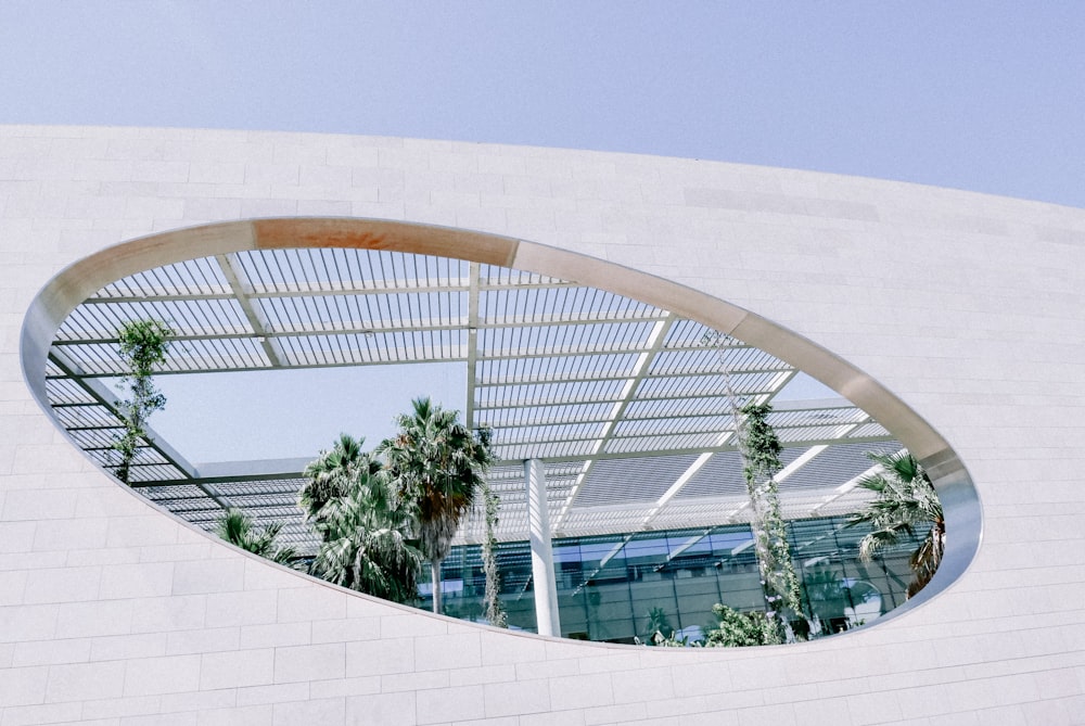 a circular mirror reflecting a building with palm trees