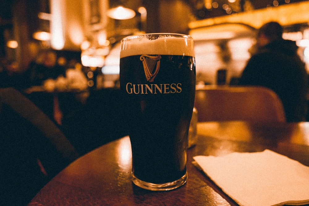 a glass of beer sitting on top of a wooden table