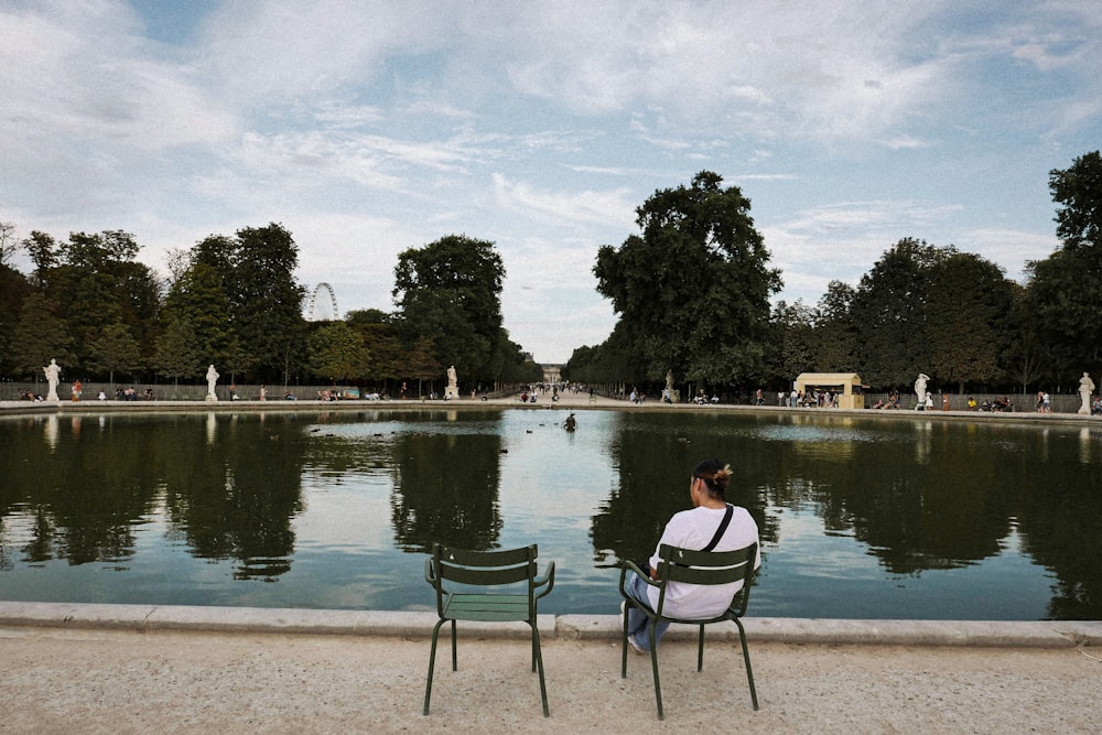 a woman sitting on a chair in front of a pond