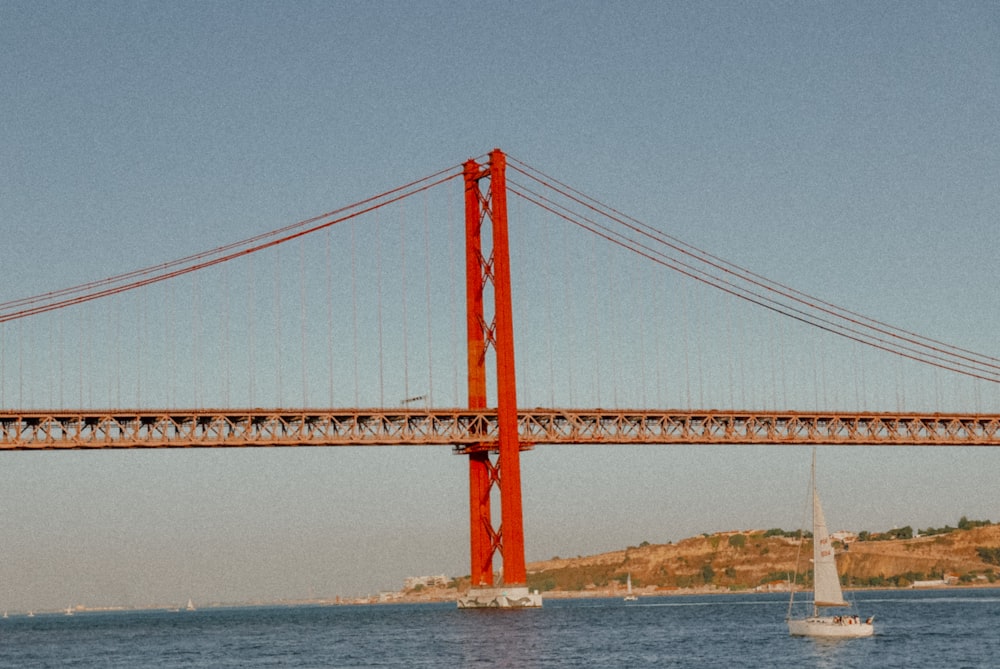 a sailboat is in the water under a bridge