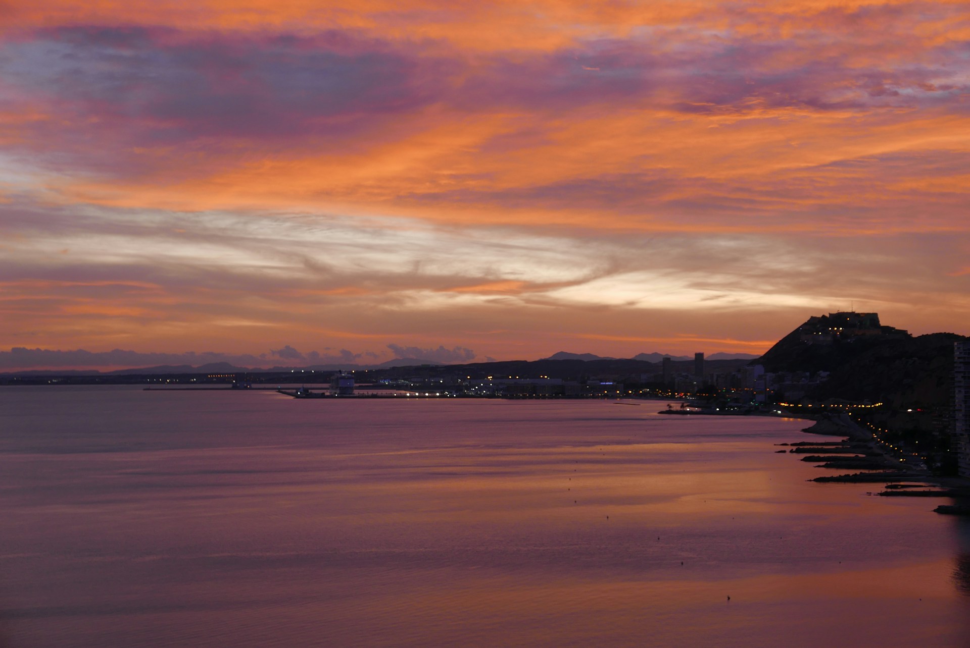 A breathtaking panoramic view of Cape Town's coastline at sunset, with Table Mountain silhouetted against the colorful sky.