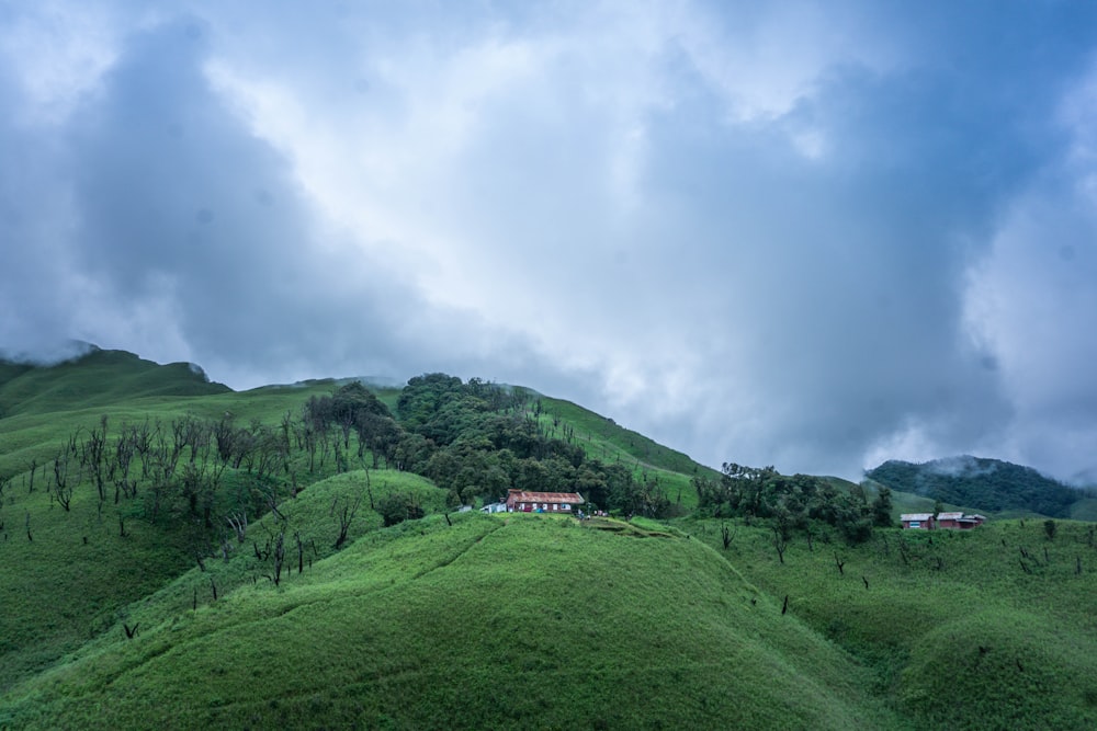 a lush green hillside with a house on top of it