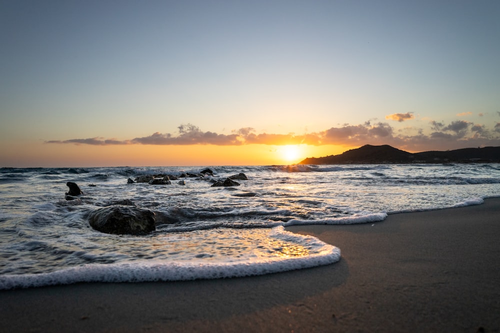 the sun is setting over the ocean on the beach