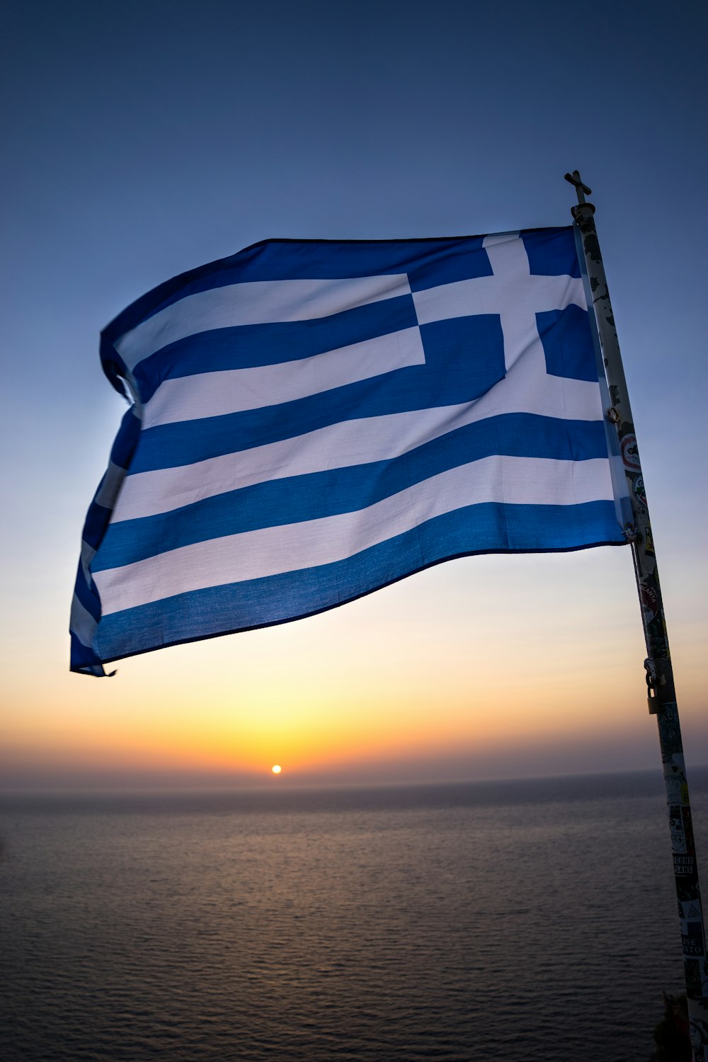 a large greek flag flying over the ocean