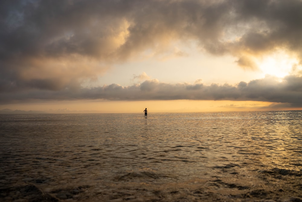 a lone person standing in the middle of a large body of water