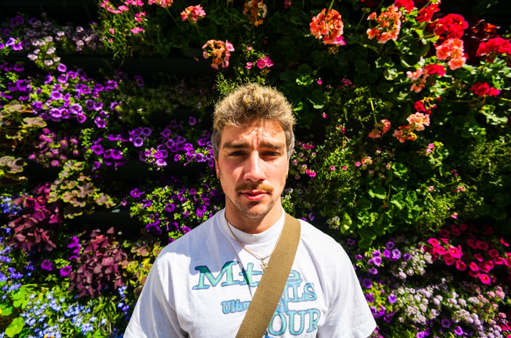 a man standing in front of a wall of flowers