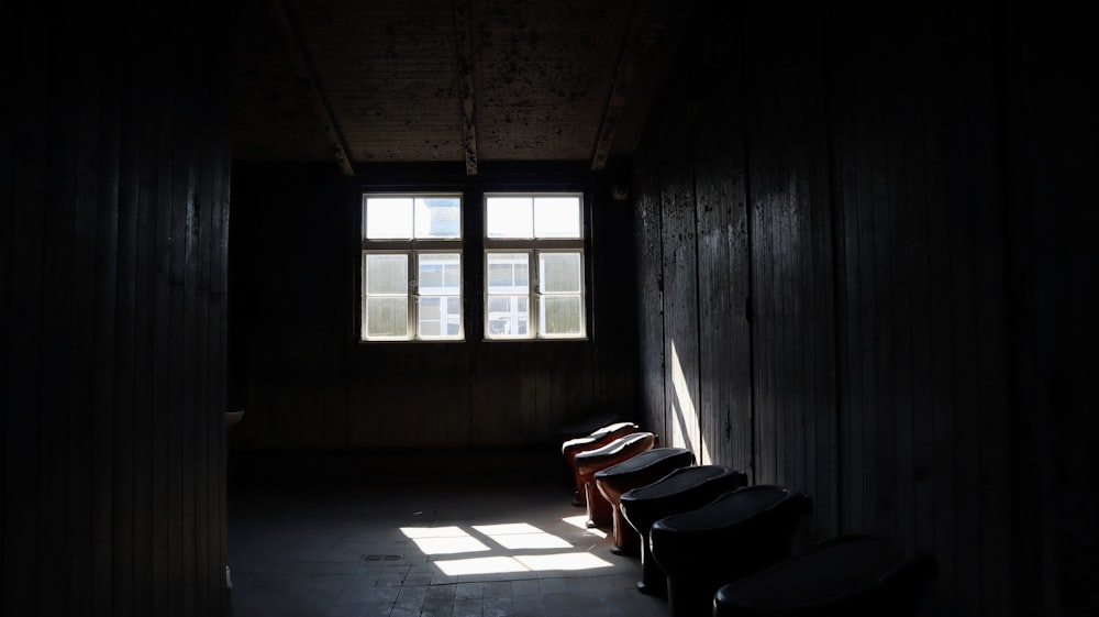 a row of chairs sitting in a dark room next to a window