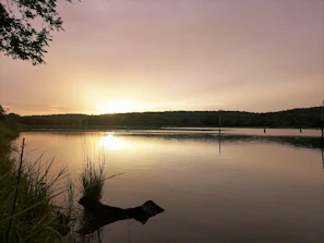 A serene lake reflecting the golden hues of a sunset, inviting calm and spiritual reflection.