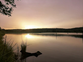 A serene lake reflecting the golden hues of a sunset, inviting calm and spiritual reflection.