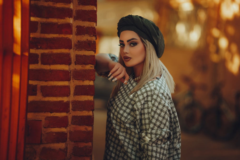 a woman leaning against a brick wall