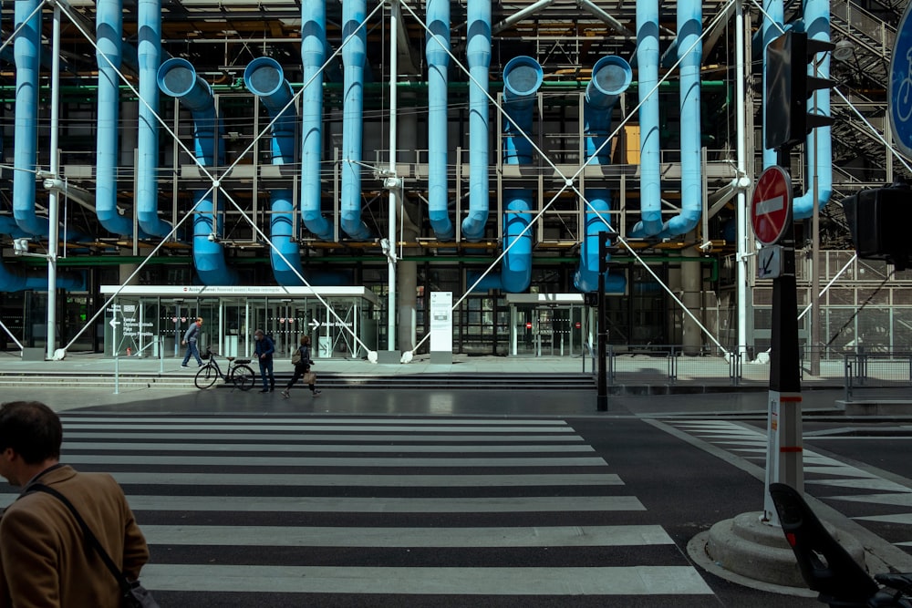 a man walking across a street next to a tall building